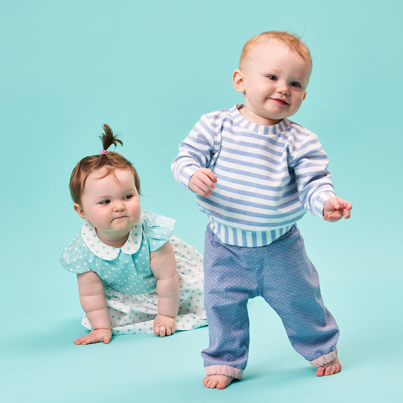 Babies wearing the Babies' Clover Reversible Trousers sewing pattern from Poppy & Jazz on The Fold Line. A trouser pattern made in cotton lawn, poplin, linen or corduroy fabrics, featuring a reversible style, elasticated waist, full length leg with contra