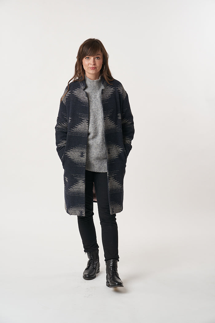 Woman wearing the Cocoon Coat sewing pattern from Sew Over It on The Fold Line. A coat pattern made in boucle, boiled wool, or melton wool fabrics, featuring a relaxed fit, fully lined, shaped collar stand, drop shoulder, full length sleeve and knee lengt
