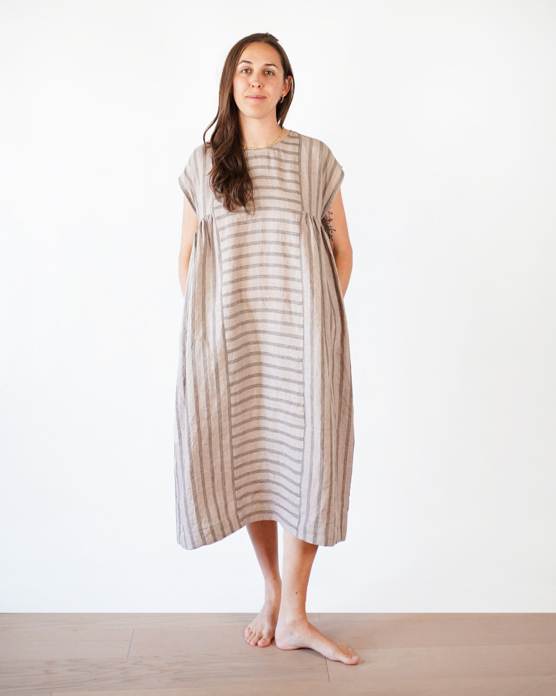 Woman wearing the Collage Gather Dress sewing pattern from Matchy Matchy on The Fold Line. A dress pattern made in light to medium weight woven fabrics, featuring a relaxed boxy fit, high waist with side gathers, in-seam pockets, midi length, round neckli