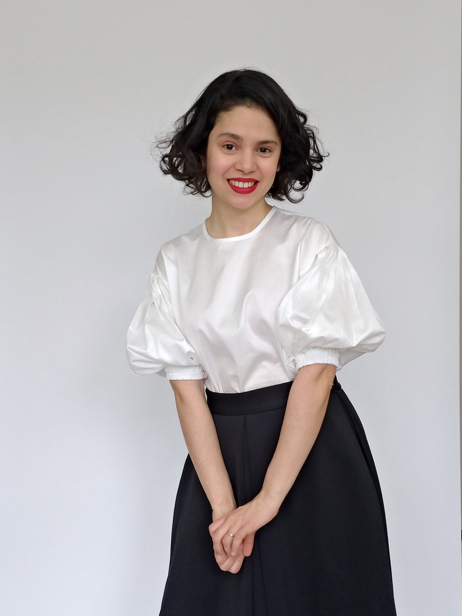 Woman wearing the Cologne Blouse sewing pattern from Bella Loves Patterns on The Fold Line. A blouse pattern made in poplin, chambray, tencel or linen fabrics, featuring a loose fit, dropped shoulders, lantern shaped elbow length sleeves. The sleeves have
