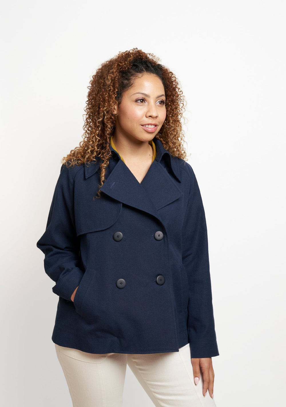 Woman wearing the Cortland Trench sewing pattern from Grainline Studio on The Fold Line. A double-breasted trench coat pattern made in cotton, tencel twill, gabardine or linen fabrics, featuring mid-hip length, raglan sleeves, storm flaps, collar, front b