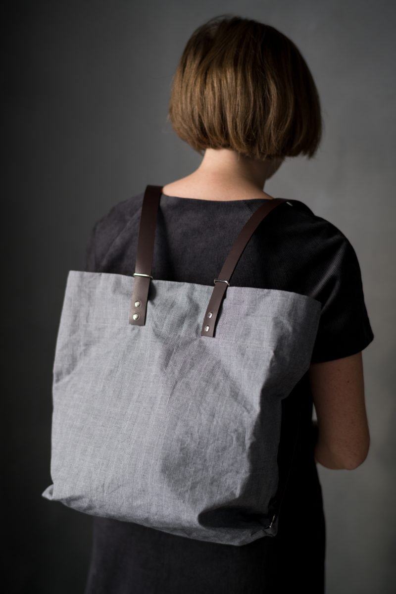 Woman wearing The Costermonger Tote sewing pattern from Merchant & Mills on The Fold Line. A tote bag pattern made in oilskin, dry oilskin, mid-heavy weight cotton canvas, drill or mid weight denim fabrics, featuring fixed length shoulder straps that are 