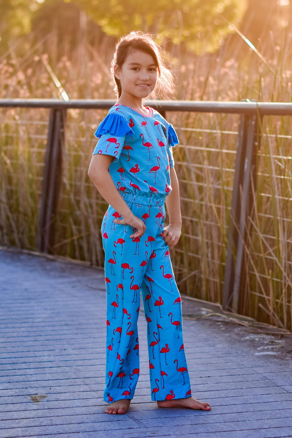 Child wearing the Children's Paradise Playsuit sewing pattern from Waves & Wild on The Fold Line. A playsuit pattern made in stretch knit fabrics, featuring a pull-on style, elasticated waist, round front neck with cross back, full length leg, short sleev