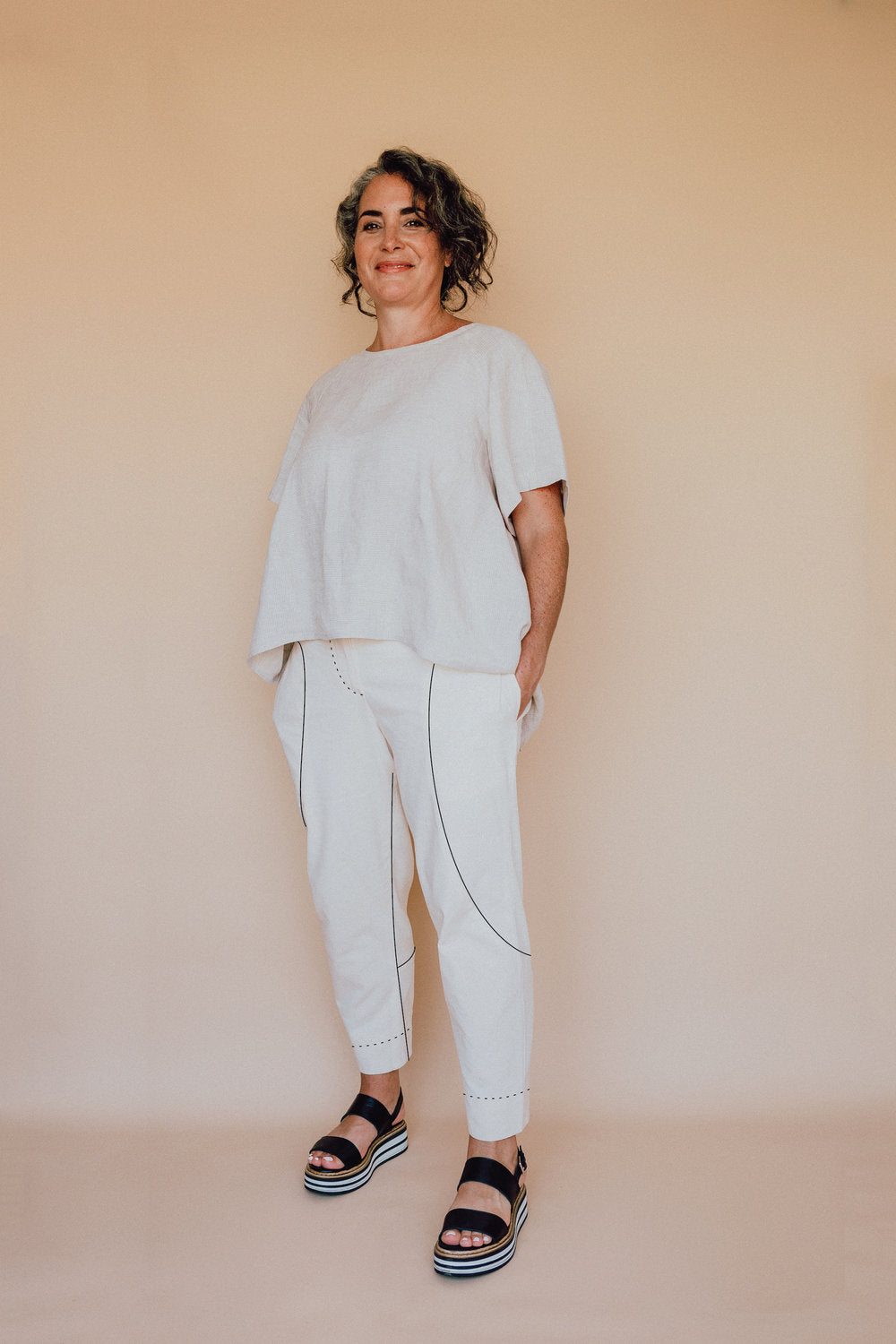 Woman wearing the Darlow Pants pattern from In the Folds on The Fold Line. A trouser pattern made in linen, linen blends, cotton drill/twill, denim, wool or silk fabrics, featuring a cropped length, tapered leg, fly front with zip closure, shaped waistban