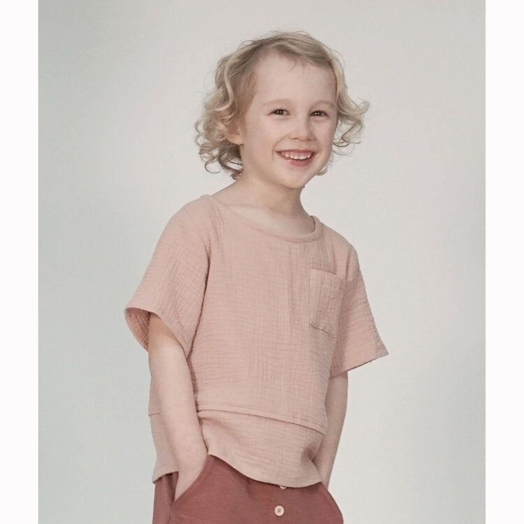 Child wearing the Child Wren Woven Tee sewing pattern from Pattern Paper Scissors on The Fold Line. A T-shirt pattern made in cotton, viscose, denim, double gauze, linen or crepe fabrics, featuring a button-through back, round neck, chest pocket, relaxed 