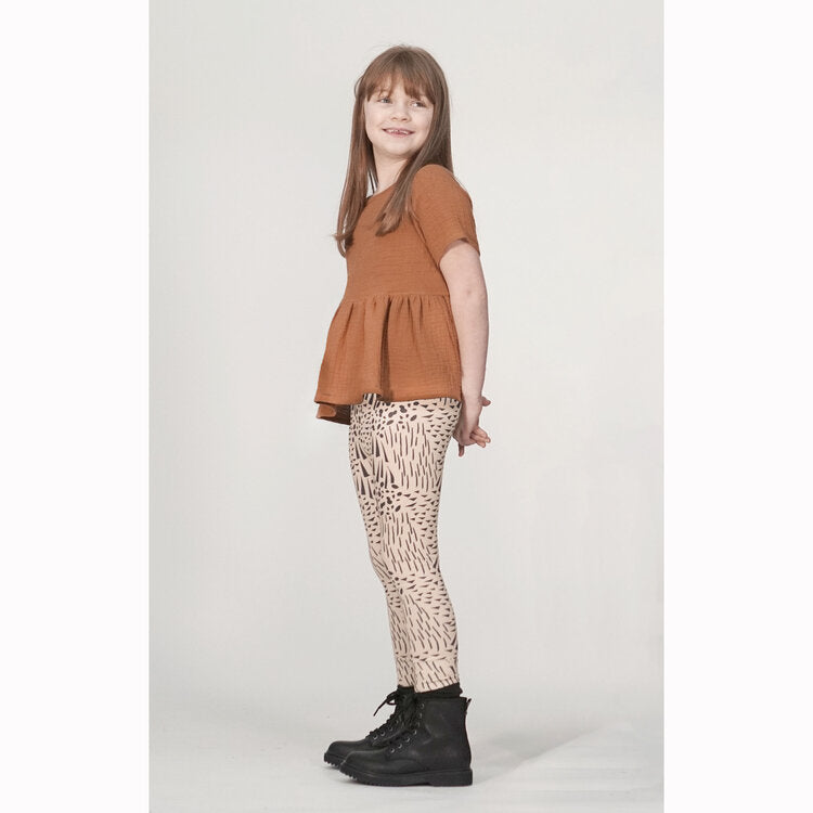 Child wearing the Child Roux Legging sewing pattern from Pattern Paper Scissors on The Fold Line. A leggings pattern made in jersey, knit, or cotton elastane fabrics, featuring an elasticated waist, and full-length leg.