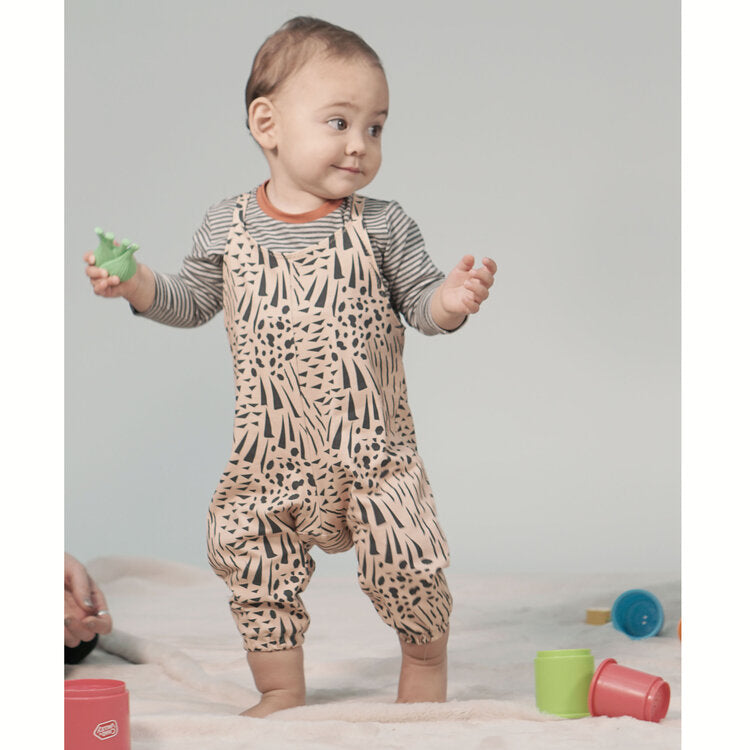 Toddler wearing the Avery Jersey Romper sewing pattern from Pattern Paper Scissors on The Fold Line. A romper pattern made in jersey, sweat, terry, stretch crepe, or knit fabrics, featuring elasticated ankle cuffs, relaxed fit, and shoulder straps.