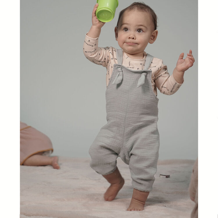 Toddler wearing the Florrie Woven Romper sewing pattern from Pattern Paper Scissors on The Fold Line. A romper pattern made in cotton, viscose, denim, double gauze, linen or crepe fabrics, featuring an ankle length, relaxed fit, bib, and adjustable tie st