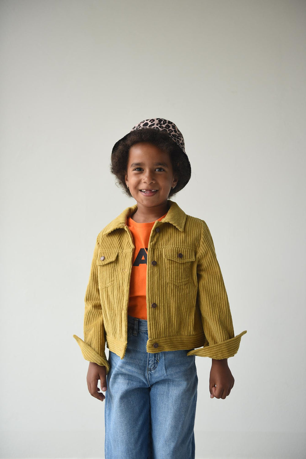 Child wearing the Child/Teen Legend Jacket sewing pattern from Fibre Mood on The Fold Line. A jacket pattern made in corduroy, cotton or denim fabrics, featuring a cropped length, two chest pockets, collar, snaps/jeans buttons fastening and full length sl