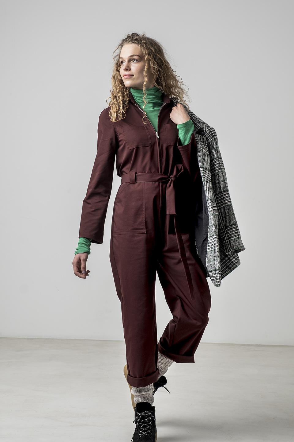 Woman wearing the Leah Jumpsuit sewing pattern from Fibre Mood on The Fold Line. A boilersuit/workwear overall pattern made in cotton, denim or corduroy fabrics, featuring topstitching, chest pockets, hip pockets, back yoke, belt and belt loops, front zip