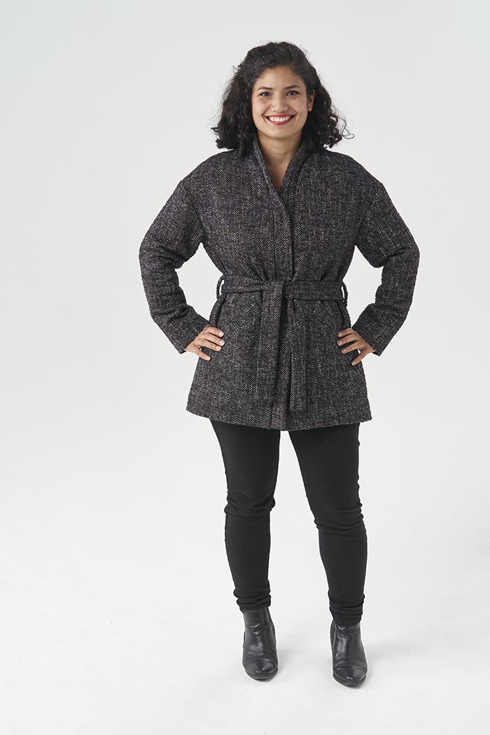 Woman wearing the Dahlia Coat sewing pattern from Sew Over It on The Fold Line. A coat pattern made in boucle, boiled wool or melton fabrics, featuring drop shoulder full length sleeves, front welt pockets, curved front band, press stud closure, belt loop