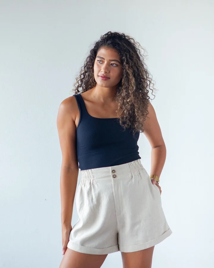Woman wearing the Dani Shorts sewing pattern from True Bias on The Fold Line. A shorts pattern made in linen, linen rayon blends, cottons or twill fabric, featuring a small paperbag high waist, elastic waist, in-seam and back pockets, front fly zip with t