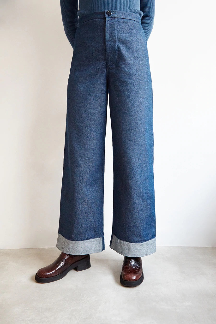 Woman wearing the Daphne Trousers sewing pattern from The Modern Sewing Co on The Fold Line. A trouser pattern made in denim or twill fabrics, featuring a high waist, wide leg with ankle cuff, fly zipper, waistband and patch pockets.