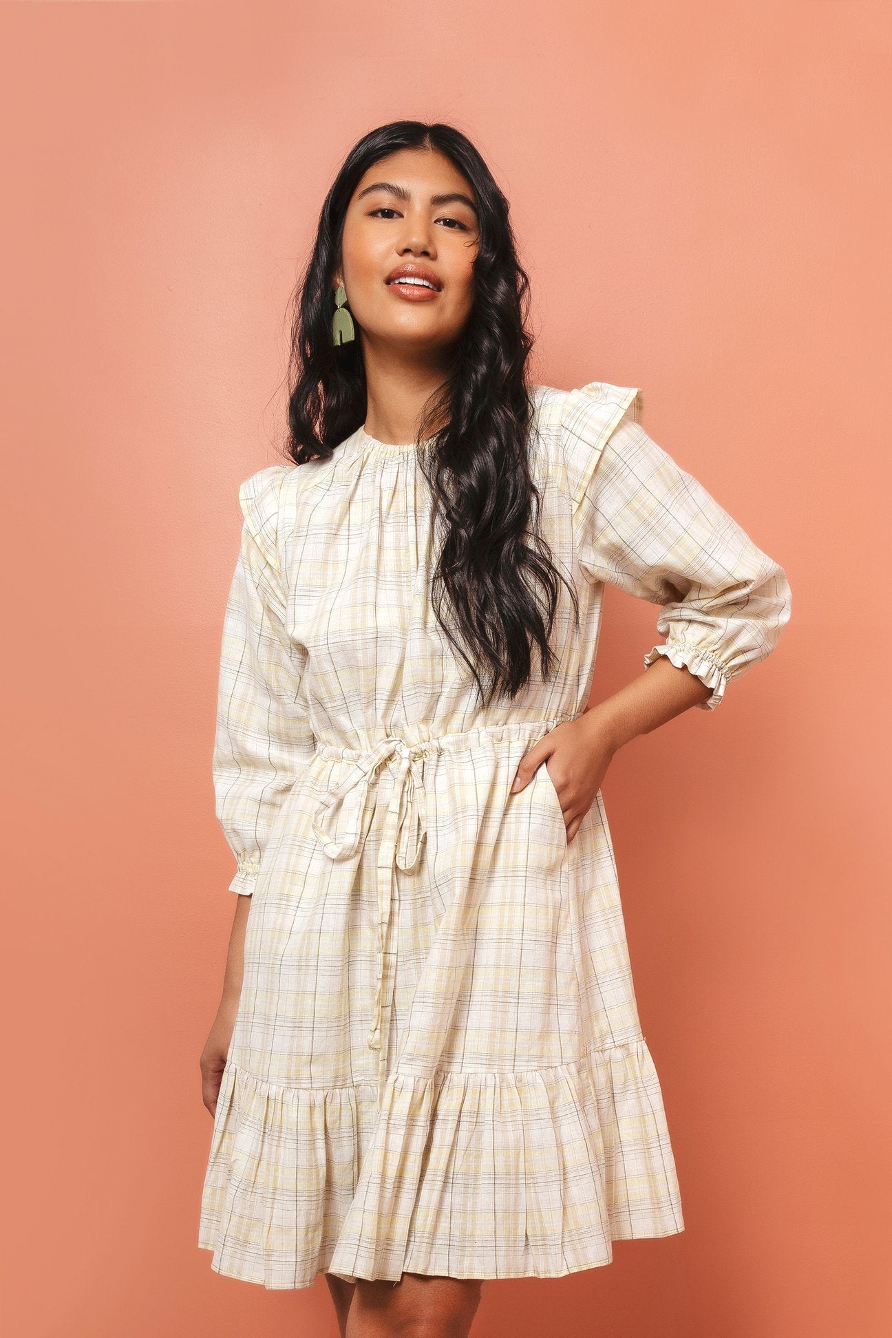 Woman wearing the Davenport Dress sewing pattern by Friday Pattern Company. A dress pattern made in cotton lawn or linen fabrics, featuring roomy pockets, full sleeves with an elastic ruffle hem, shoulder flutter detail, a drawstring waist and tiered hem.