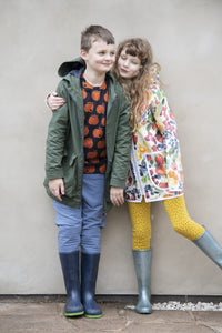 Children wearing the David Raincoat sewing pattern from Bobbins and Buttons on The Fold Line. A unisex raincoat pattern made in laminated cotton, polyurethane, coated cotton, cotton drill or denim fabrics, featuring a zip-front, bound edges, raglan sleeve