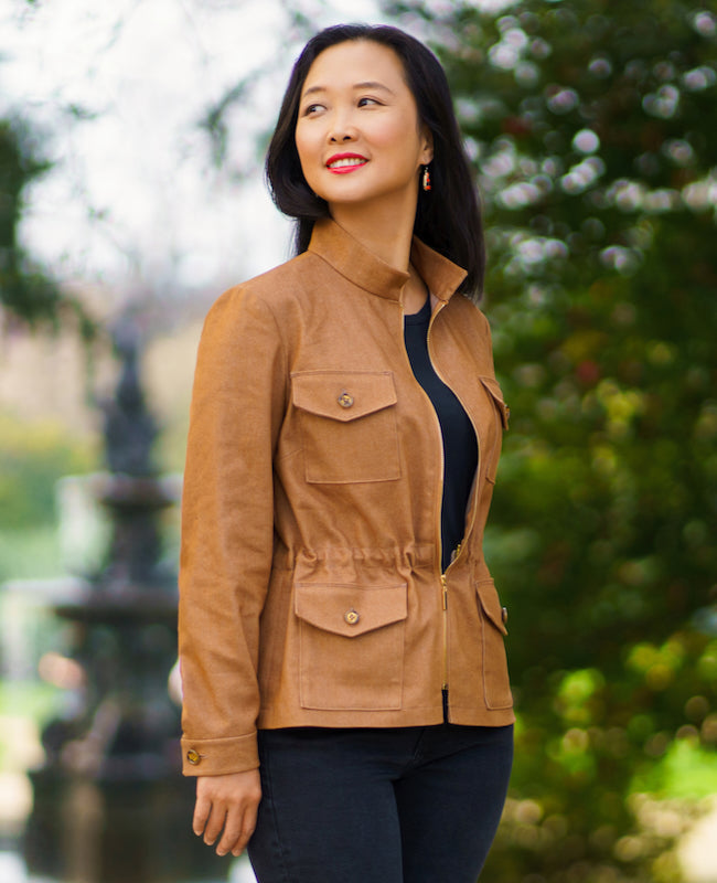 Woman wearing the Delaware Jacket sewing pattern from Itch to Stitch on The Fold Line. A jacket pattern made in twill, broadcloth, or linen fabric, featuring a stand-up collar, centre front exposed zipper, cinched waist, two-piece set-in sleeves with cuff