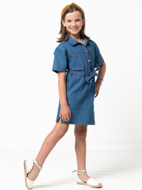 Child wearing the Child/Teen Demi Dress sewing pattern from Style Arc on The Fold Line. A dress pattern made in denim, cotton drill or heavy linen fabrics, featuring collar and stand, short sleeves, front button tab, waist tie, chest patch pockets, skirt 