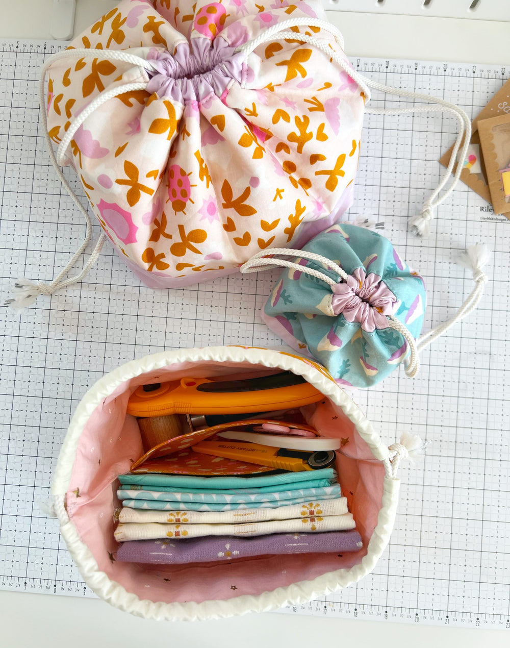 Photo of the Divided Drawstring Pouch sewing pattern from Lou Orth Designs on The Fold Line. A bag pattern made in quilting cotton fabric, featuring a slip pocket divider in the middle, perfect for organising and storing your craft projects or supplies.