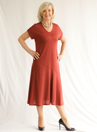 Woman wearing the Doreen Knit Dress sewing pattern from Style Arc on The Fold Line. A knit dress pattern made in knit jersey, marino knit or T-shirt knit fabrics, featuring a V-neck, slip-on style, extended shoulder line, double sleeve bands, asymmetrical