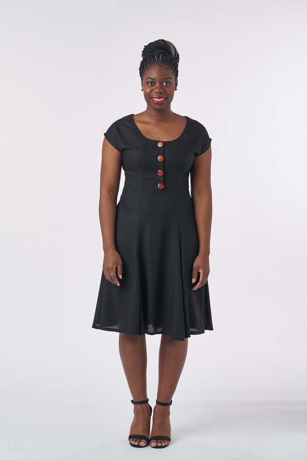 Woman wearing the Doris Dress sewing pattern from Sew Over It on The Fold Line. A knee length dress with a scoop neck and short grown-on sleeves.