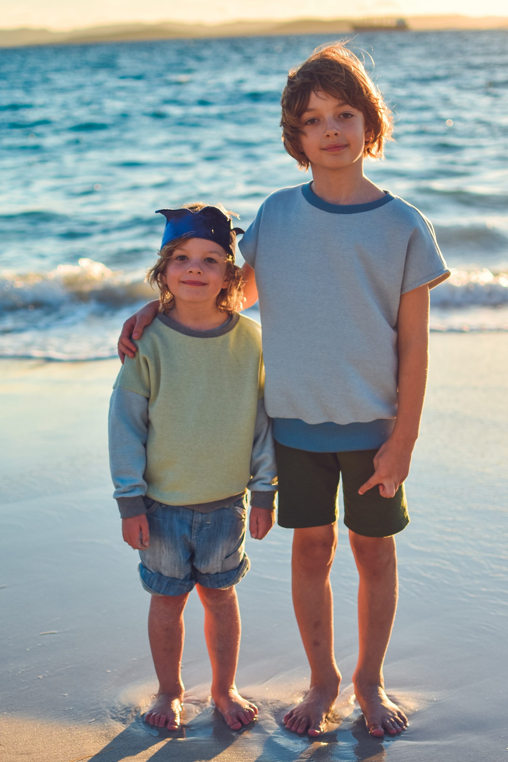 Children wearing the Baby/Child Driftwood Dolman Sweatshirt sewing pattern from Waves and Wild on The Fold Line. A sweatshirt pattern made in medium-weight knit fabric, featuring a relaxed fit, short or long sleeves, round neck and ribbing to the cuff and