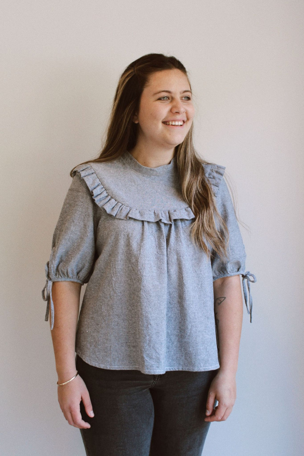 Woman wearing the Dua Blouse sewing pattern from Makyla Creates on The Fold Line. A top pattern made in linen, cotton, double gauze, crepe de chine, poplin, silk, rayon or tencel fabrics, featuring a relaxed fit, stand collar, button up shoulder placket c