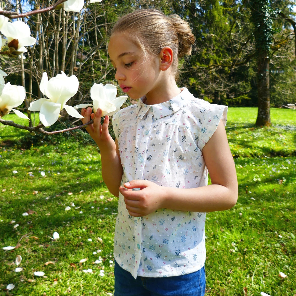 Child wearing the Dulcine Shirt sewing pattern from Petits D’om on The Fold Line. A blouse pattern made in poplin, batiste, Liberty, plumetis, cotton satin, tencel, viscose or double gauze fabrics, featuring a front yoke with gathers, cap sleeves, front b