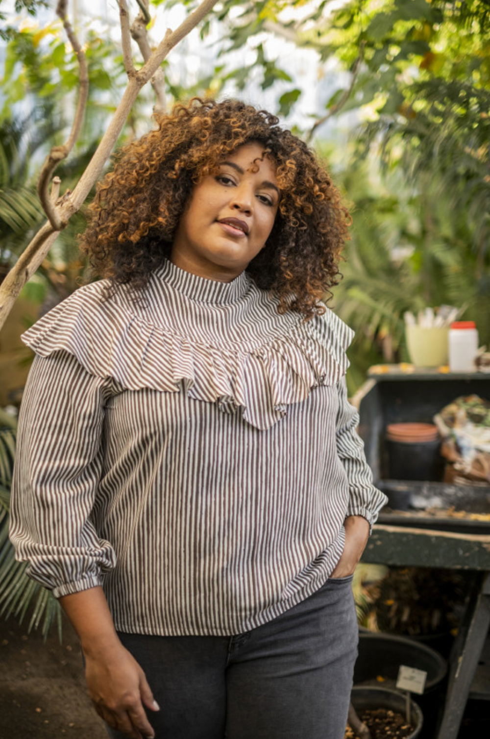 Woman wearing the Edith Top sewing pattern from Fibre Mood on The Fold Line. A top pattern made in double gauze, viscose (crepe), chambray, lyocell, poplin, baby wale corduroy or broderie anglaise fabrics, featuring an understated collar, ruffled trim tha