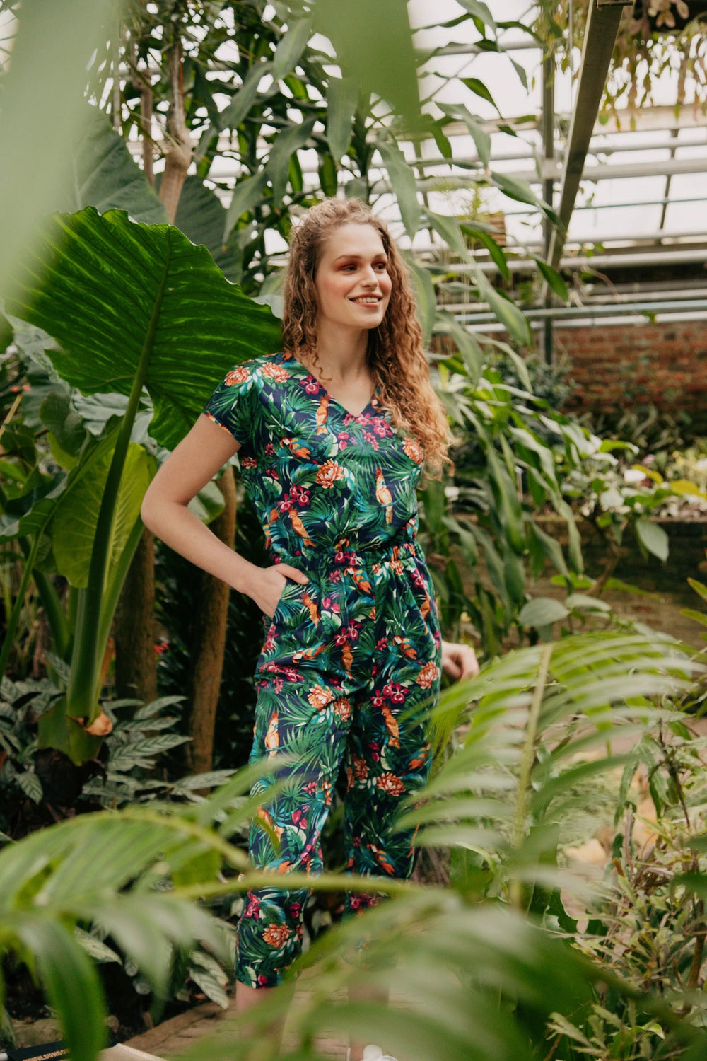 Woman wearing the Elle Jumpsuit sewing pattern from Atelier Jupe on The Fold Line. A jumpsuit pattern made in cotton, viscose or tencel fabrics, featuring a loose top, bust darts, V-neckline, back slit with button closure, below calf length, elasticated w