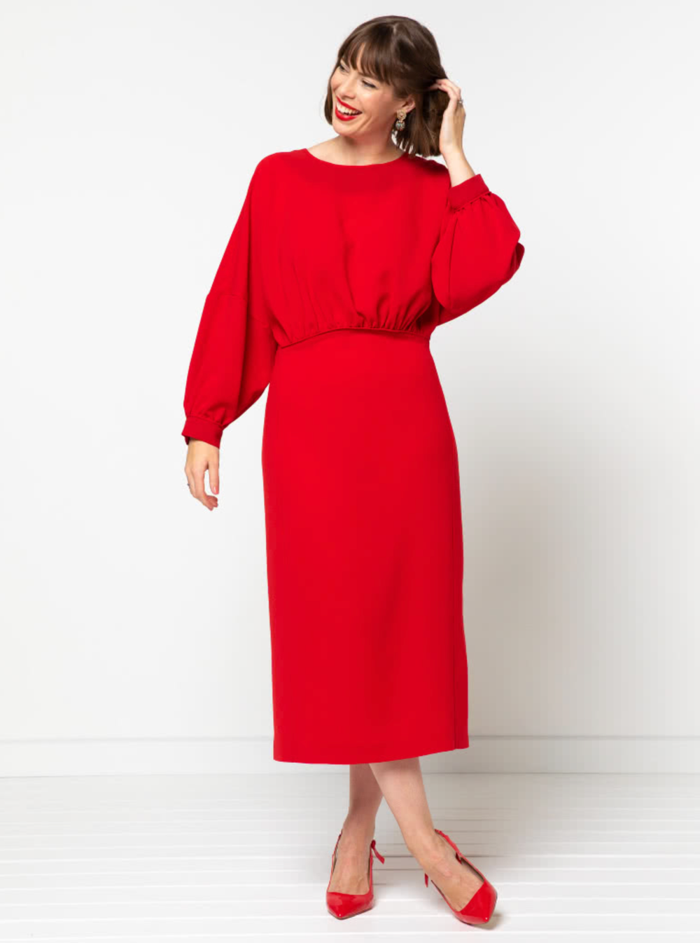 Woman wearing the Elsbeth Woven Dress sewing pattern from Style Arc on The Fold Line. A dress pattern made in linen, silk , viscose or cotton fabrics, featuring a gathered front bodice, extended shoulder line, full length cuffed sleeves, fitted, panelled 