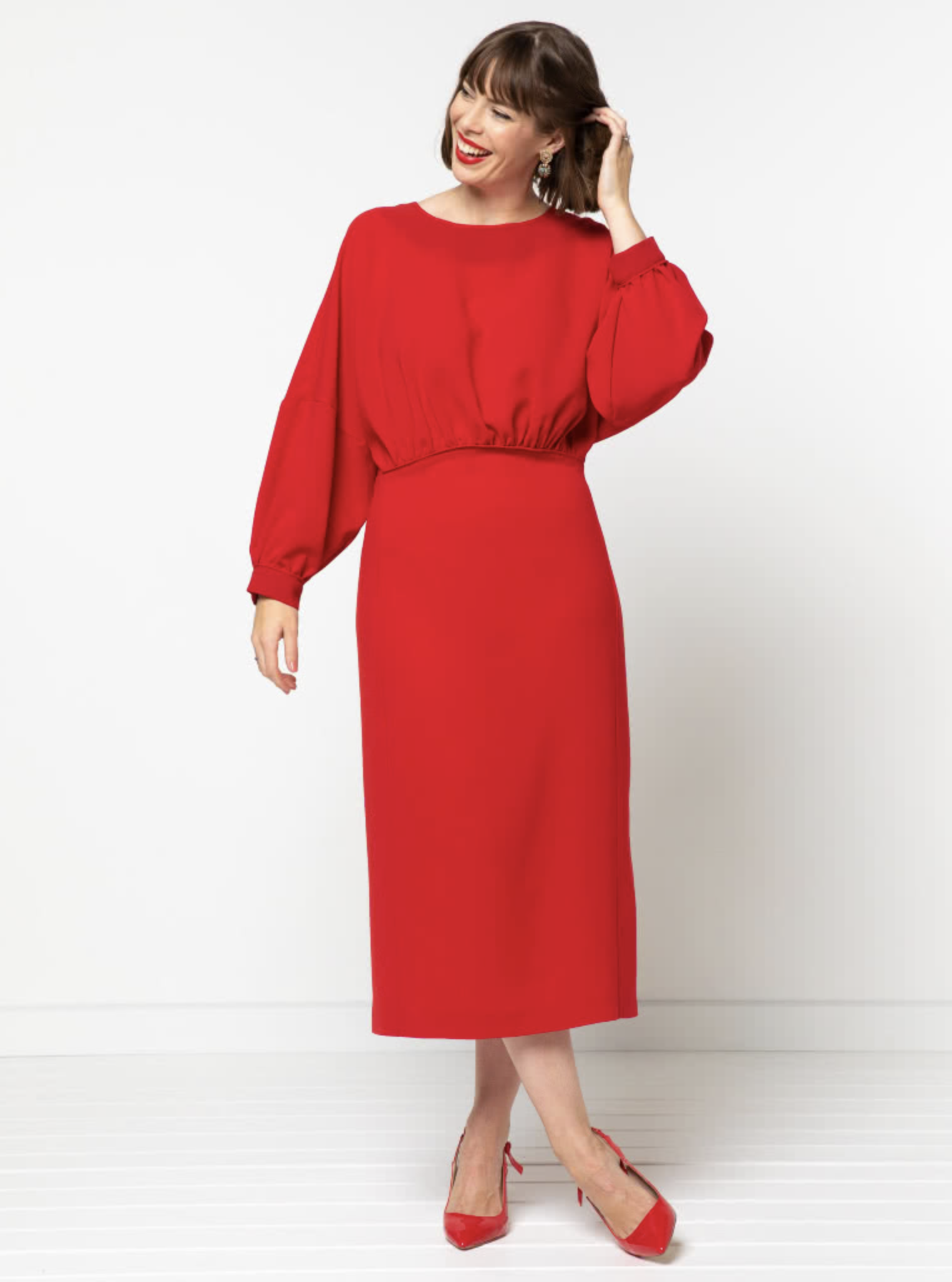 Woman wearing the Elsbeth Woven Dress sewing pattern from Style Arc on The Fold Line. A dress pattern made in linen, silk , viscose or cotton fabrics, featuring a gathered front bodice, extended shoulder line, full length cuffed sleeves, fitted, panelled 