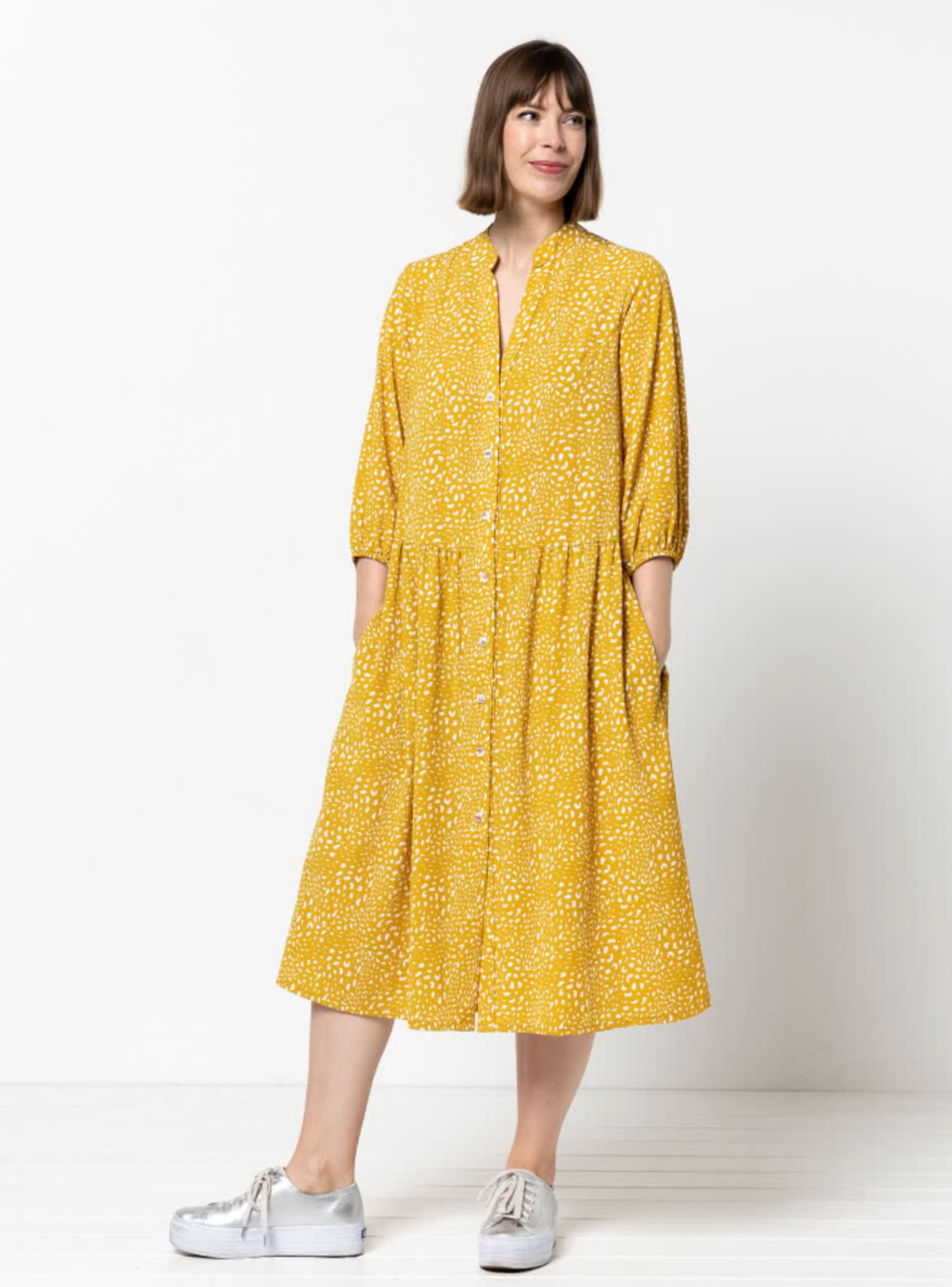 Woman wearing the Emerson Woven Dress sewing pattern from Style Arc on The Fold Line. A dress pattern made in rayon, crepe or silk fabrics, featuring a low waist, button through, mandarin collar, gathered skirt, in-seam pockets. 3/4 length sleeves with el