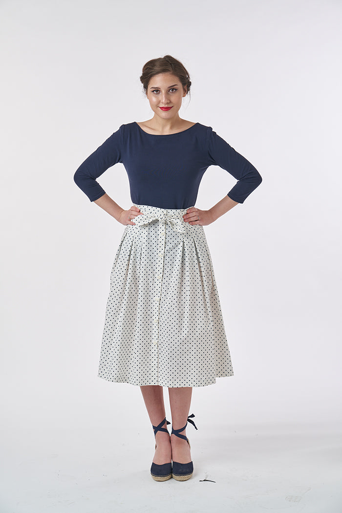 Woman wearing the Emmeline Skirt sewing pattern from Sew Over It on The Fold Line. A shirt pattern made in cotton lawn, poplin, voile, linen, viscose linen and broderie anglaise fabrics, featuring a high-waist, button front, half-stitched inverted box ple