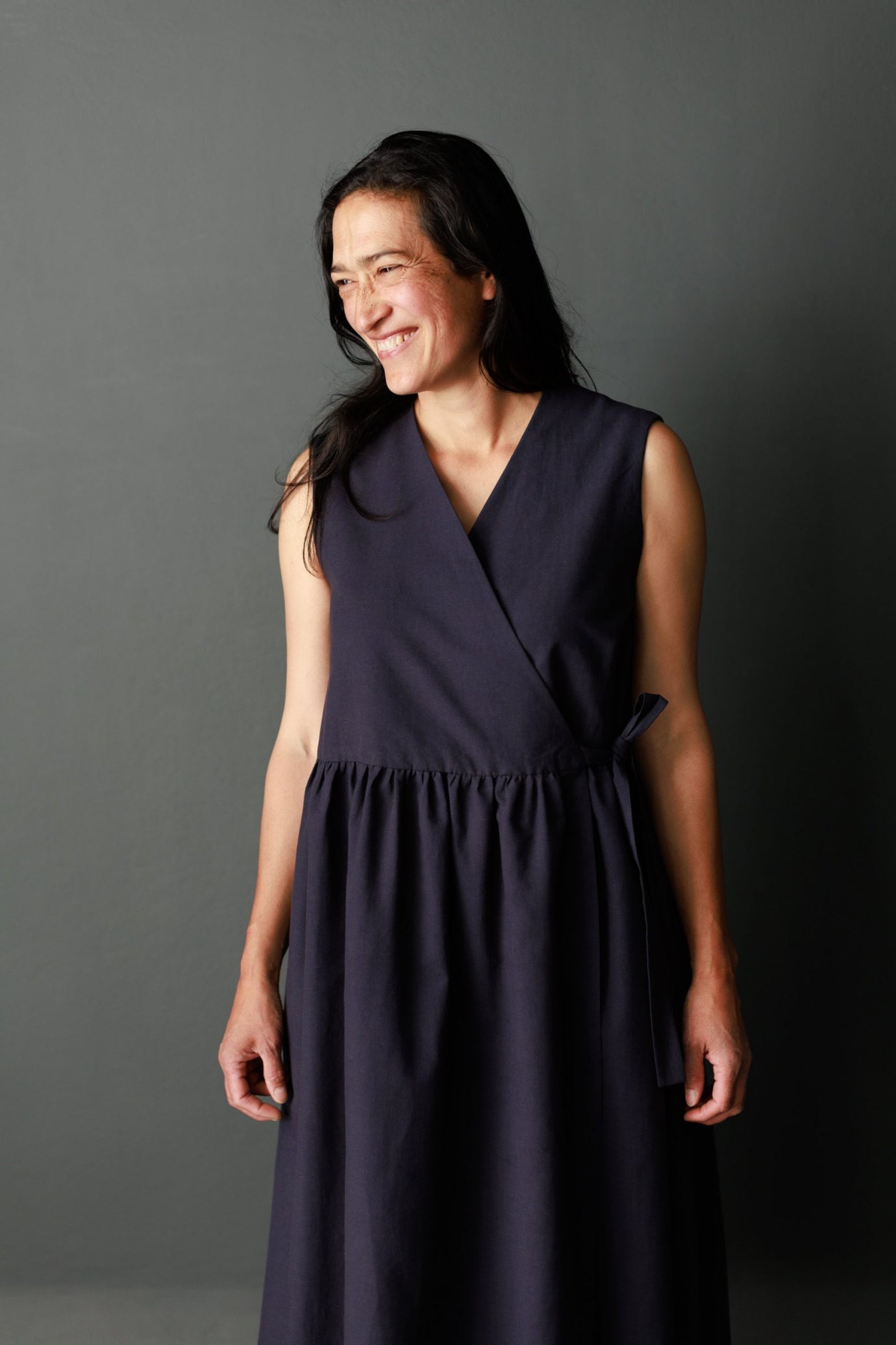 Woman wearing The Etta Dress sewing pattern from Merchant & Mills on The Fold Line. A sleeveless, wrap dress pattern made in linen, brushed cotton, cotton lawn, cotton poplin, tencel, Indian handlooms, lightweight baby cord or cotton double gauze fabrics 