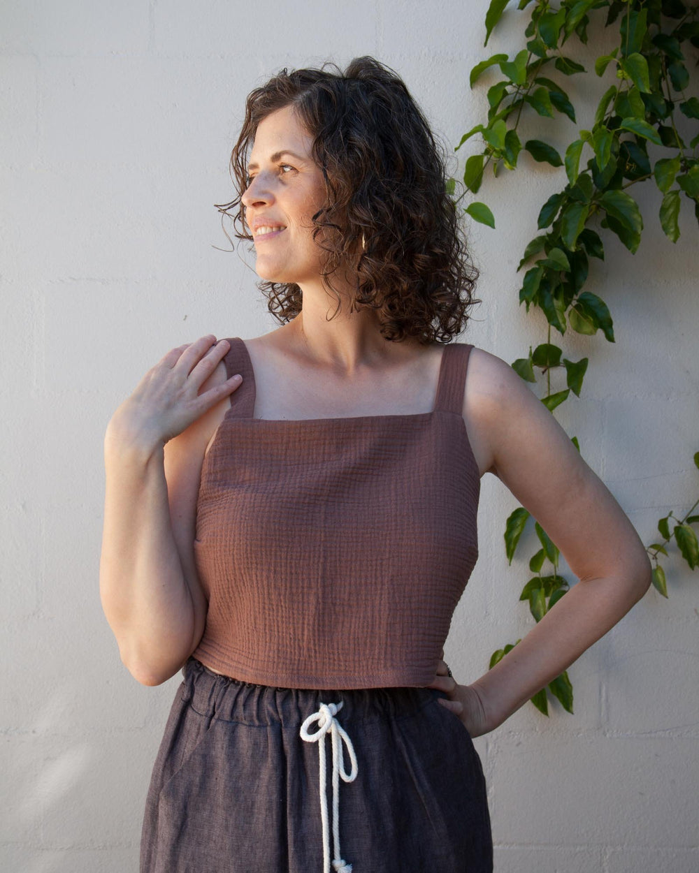 Woman wearing the Eva Top sewing pattern from Sew DIY on The Fold Line. A top pattern made in linen, chambray, cotton lawn, poplin, double gauze, rayon, and crepe de chine fabrics, featuring a semi-fit, cropped length, square neckline, bust darts, bust cu