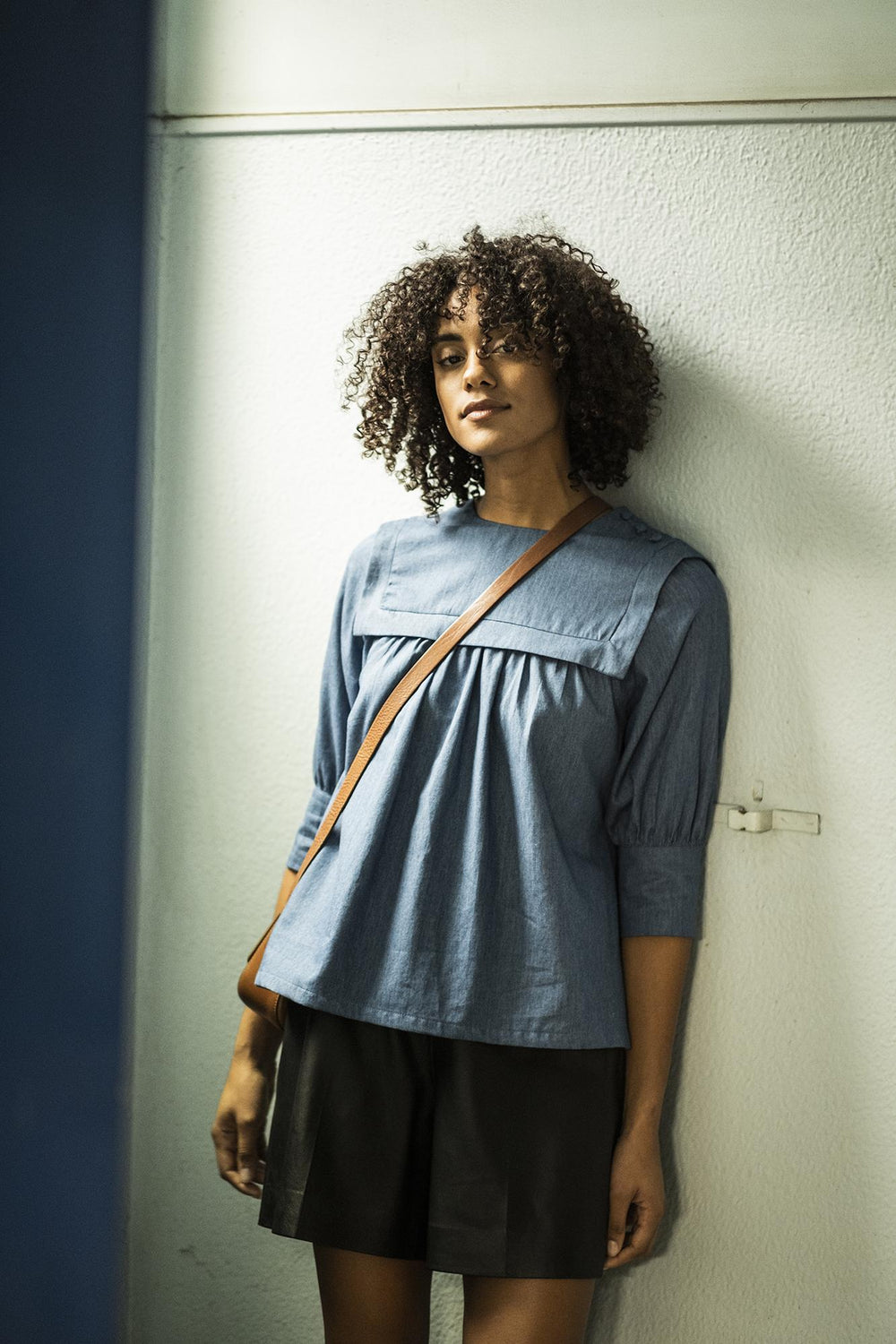 Woman wearing the Harmony Top sewing pattern from Fibre Mood on The Fold Line. A top pattern made in chambray, Tencel, linen, (viscose) crêpe or woven viscose fabrics, featuring a sailor collar, front and back yoke with gathers, button flap on the shoulde