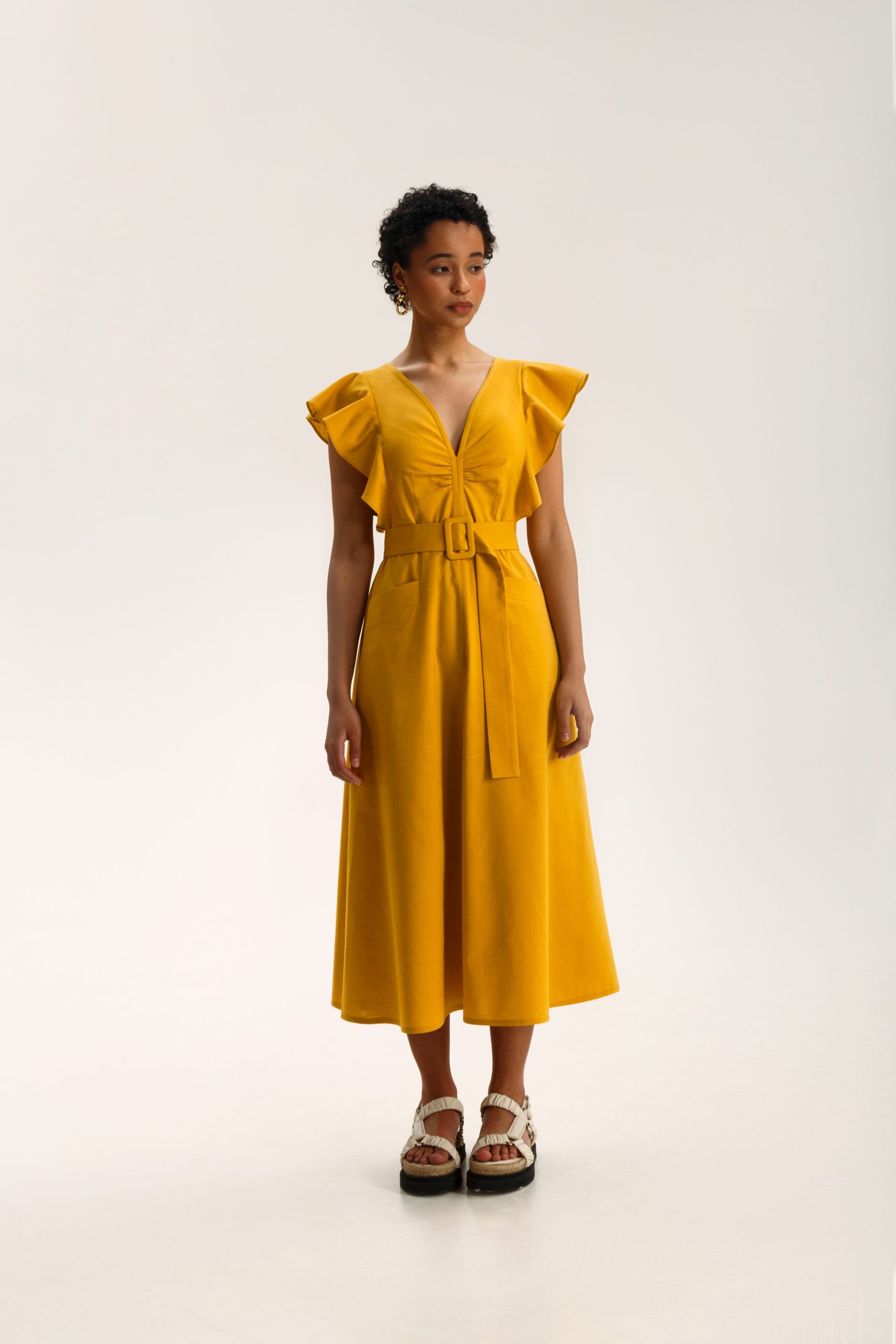 Woman wearing the Felicia Dress sewing pattern from Vikisews on The Fold Line. A dress pattern made in viscose, crepe, linen, poplin, satin, silk, cotton eyelet fabric or dress-weight denim fabrics, featuring a close-fit, accentuated waist, waist seam, de