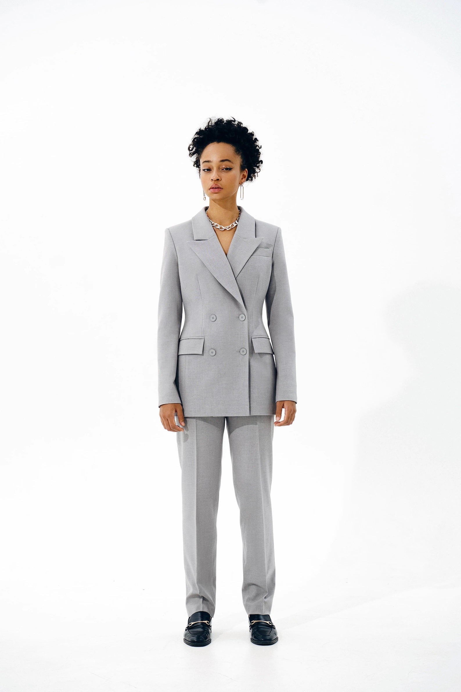 Woman wearing the Fernanda Blazer sewing pattern from Vikisews on The Fold Line. A blazer pattern made in wool suiting or gabardine fabrics, featuring a semi-fit, lined, accentuated waist, shoulder and waist darts, vertical bust darts, welt pockets, long 