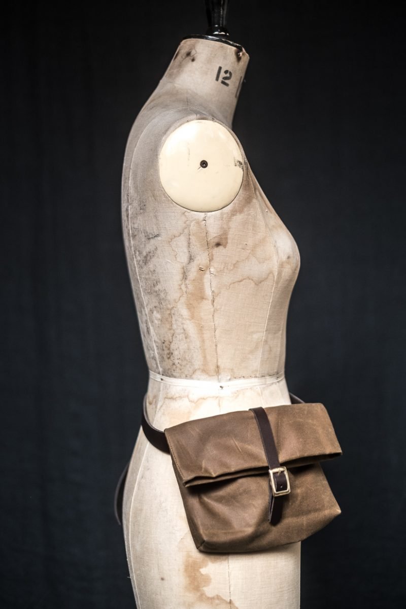 Mannequin showing the Field Belt pattern from Merchant and Mills on The Fold Line. A waist bag pattern made in oilskin, dry oilskin or cotton canvas fabrics, featuring a leather waist belt with buckle, fold-over fabric top and second strap with buckle clo