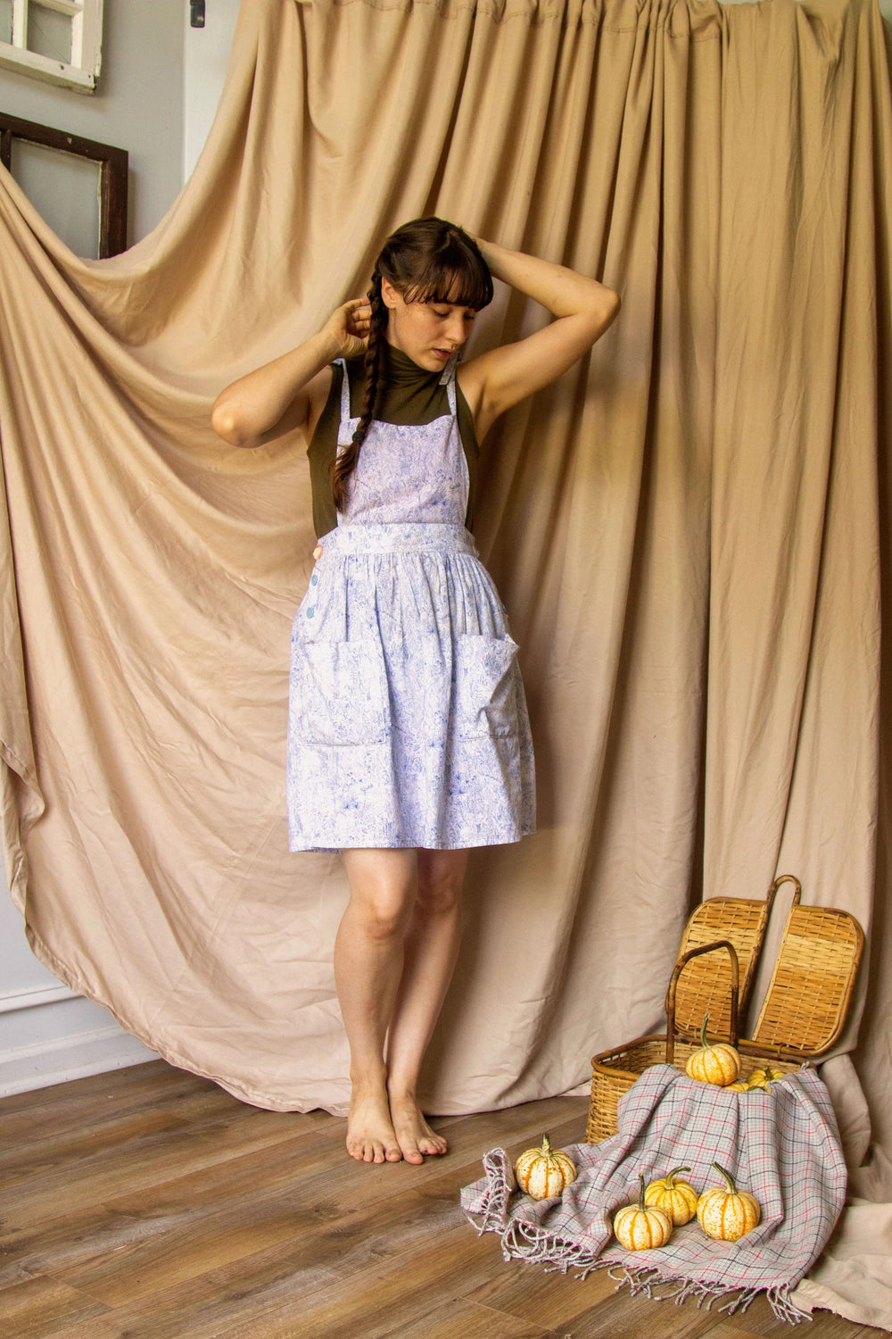 Woman wearing the Fleur Pinafore sewing pattern from Untitled Thoughts on The Fold Line. A pinafore pattern made in linen, chambray, cotton poplin, rayon/linen blend, quilting cotton, mid- twill or light to mid-weight corduroy fabrics, featuring tie shoul