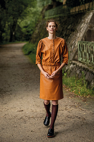 Woman wearing the Flora Dress sewing pattern from Fibre Mood on The Fold Line. A dress pattern made in denim, cotton twill, poplin, chambray, corduroy, leather(ette) or woven jacquard fabrics, featuring, snap bodice closure, round neckline, front and back