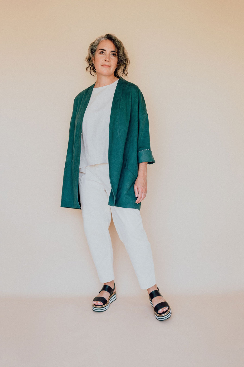 Woman wearing the Flynn Jacket pattern from In the Folds on The Fold Line. A jacket pattern made in denim, cottons canvas, drill or heavyweight linen fabrics, featuring a loose fitting silhouette, drop shoulder, wrap round collar, inverted box-pleat in th