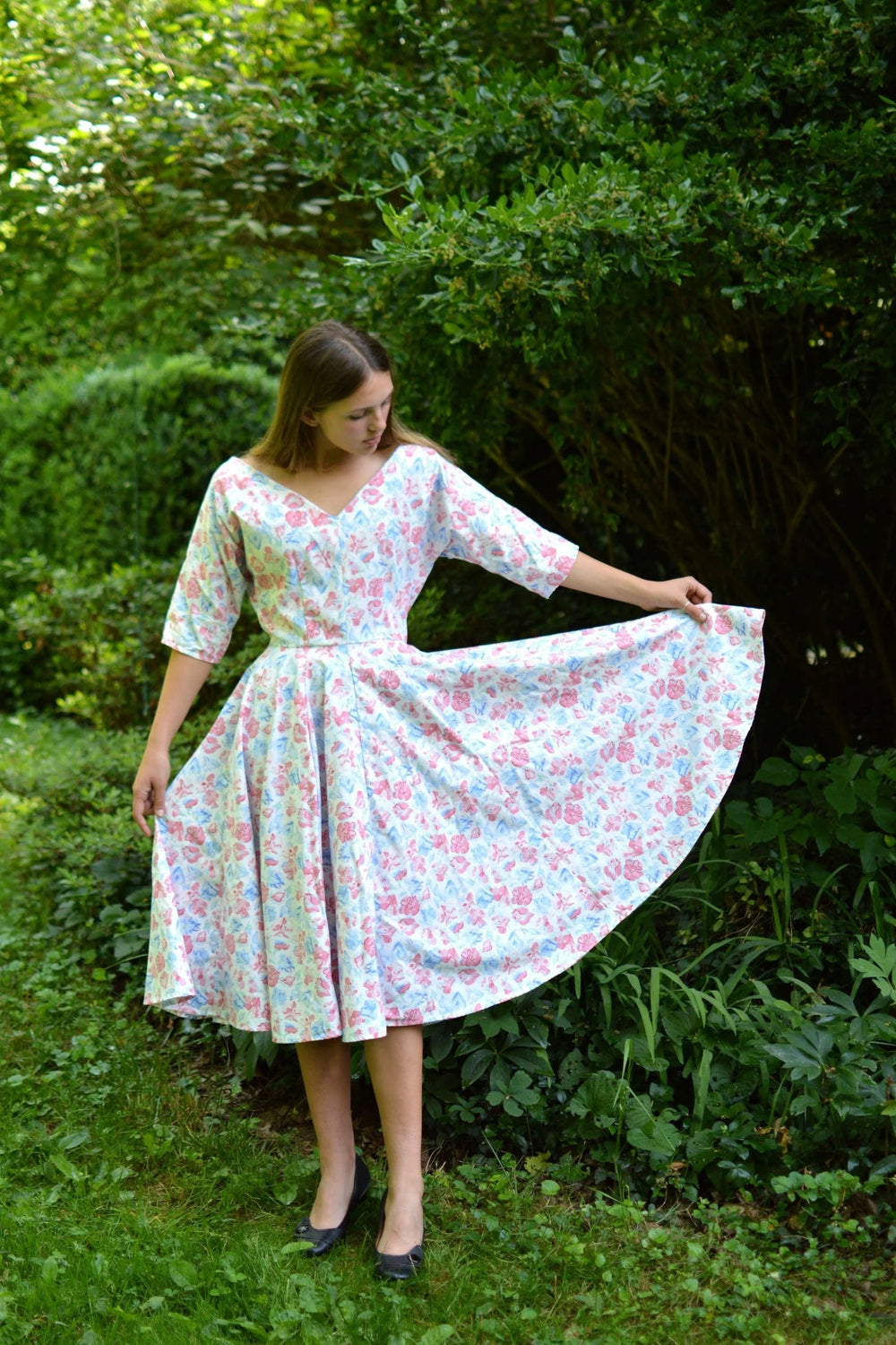 Woman wearing the 241 Fifties Fit and Flair Dress sewing pattern from Folkwear on The Fold Line. A dress pattern made in soft wools such as crepe, challis, jersey, medium weight taffeta, cotton, and blend fabrics, featuring dolman sleeves, fitted waist, g