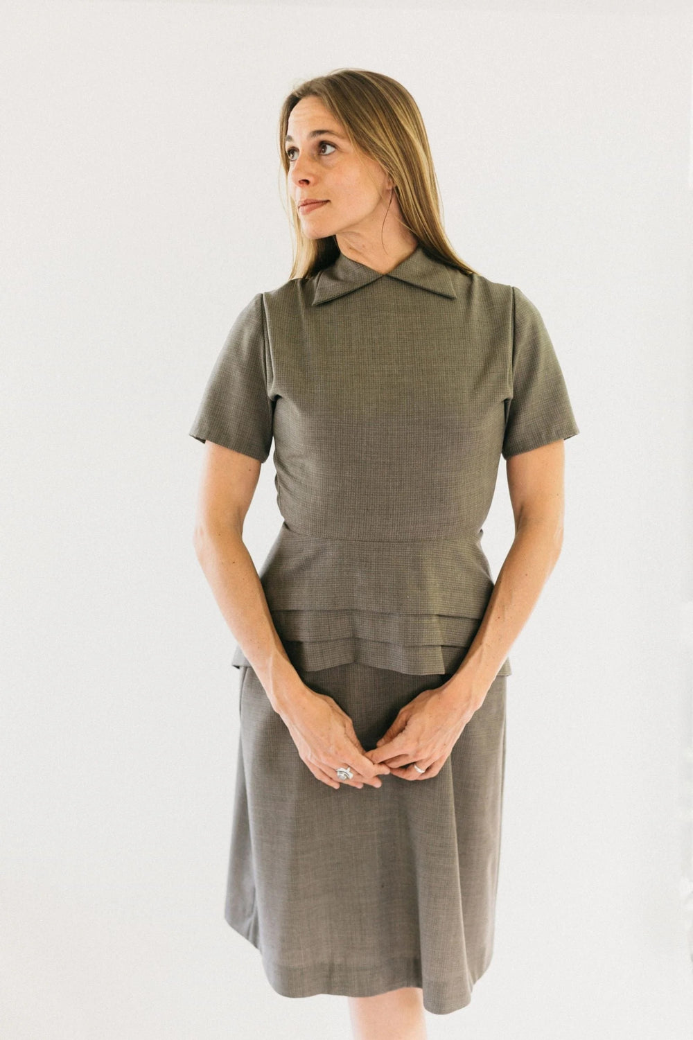 Woman wearing the 249 1930s Day Dress sewing pattern from Folkwear on The Fold Line. A dress pattern made in rayon, medium-weight silk, or microfibre fabrics, featuring a round neck with collar points, peplum, back zipper, dropped waistline, short sleeves