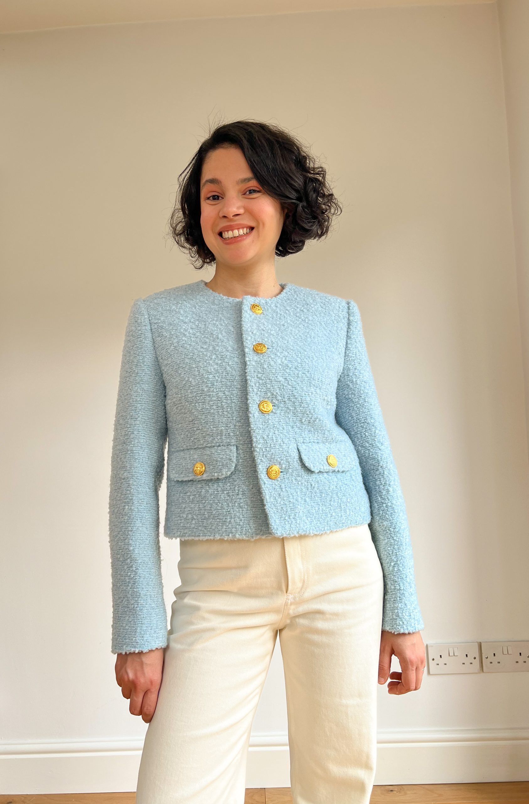 Woman wearing the Abbie Skirt sewing pattern from Bella Loves Patterns on The Fold Line. A jacket pattern made in tweed, boucle or Chanel fabrics, featuring a boxy silhouette, single-breasted, round neckline, bust darts, shoulder pads, two-piece sleeves w