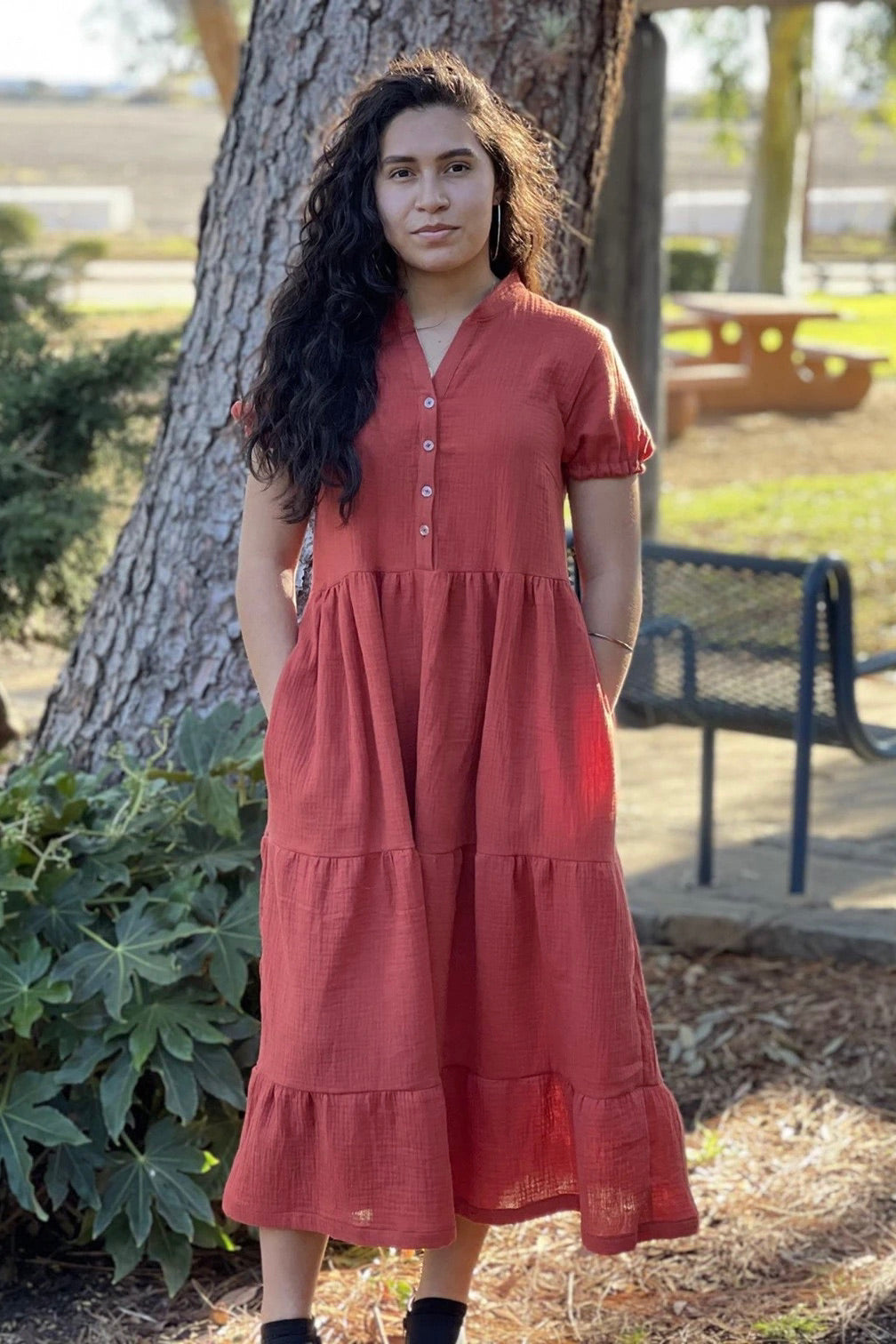Woman wearing the Freedom Dress sewing pattern from Wardrobe by Me on The Fold Line. A dress pattern made in cotton, viscose, Tencel or silk fabrics, featuring a V-neck, button front bodice, short sleeves with elastic cuffs, in-seam pockets, midi length a