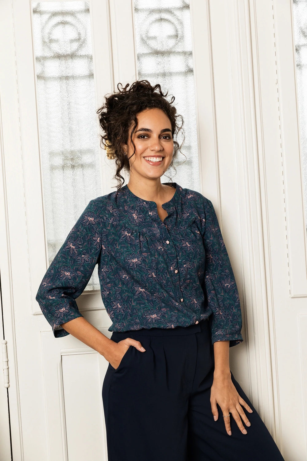 Woman wearing the Frida Blouse sewing pattern from Atelier Jupe on The Fold Line. A blouse pattern made in cotton, viscose, linen or tencel fabrics, featuring a front yoke with gathers, back yoke with inverted pleat, button placket, three-quarter sleeves 