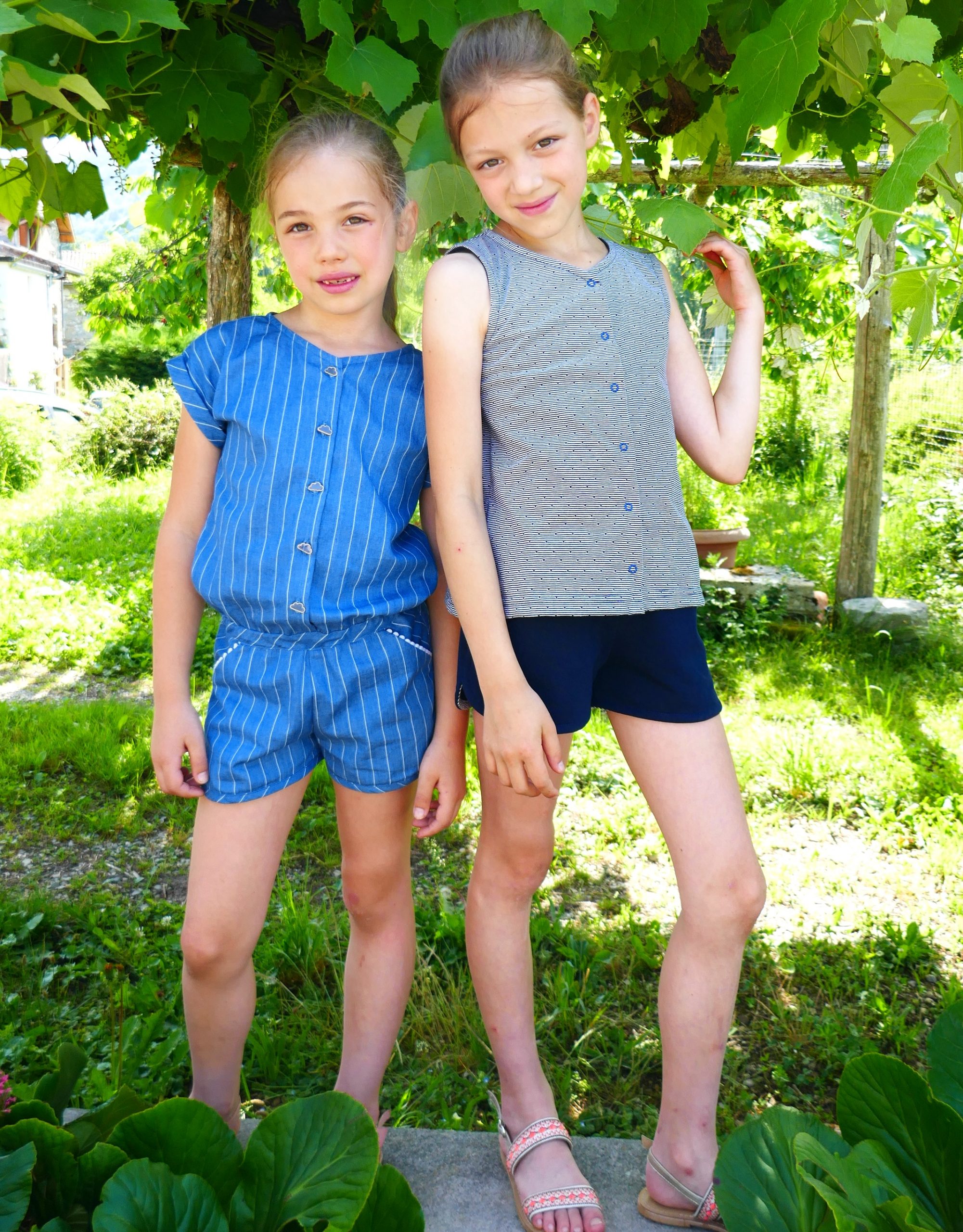 Children wearing the Gobolino Jumpsuit, Top and Shorts sewing pattern from Petits D’om on The Fold Line. A jumpsuit, top and shorts pattern made in woven or stretch fabrics, featuring a tank top with V-neckline and button front. Shorts are short with roun