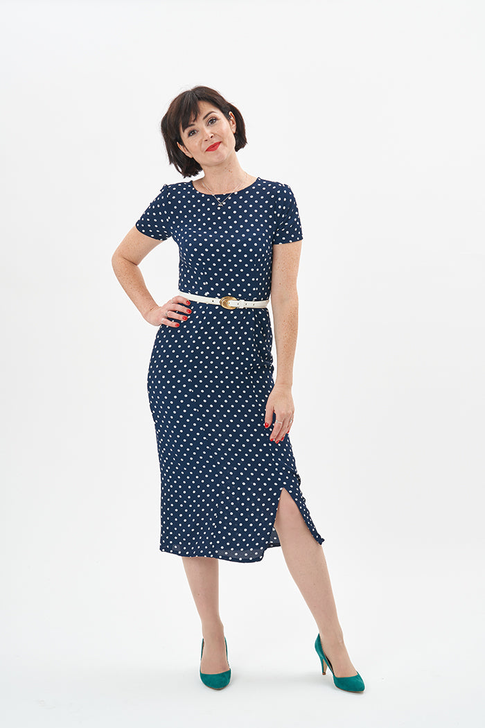 Woman wearing the Giselle Dress sewing pattern from Sew Over It on The Fold Line. A semi-fitted sheath dress pattern made in rayon, viscose or crepe fabrics, featuring a double darted bodice, short sleeves, midi length with off centre front slit, round ne