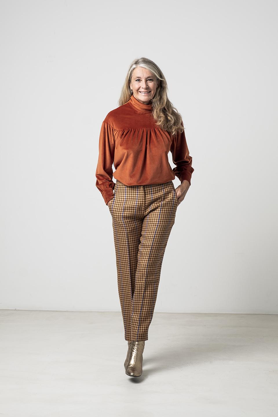 Woman wearing the Glory Top sewing pattern from Fibre Mood on The Fold Line. A top pattern made in woven or knit fabrics, featuring a standing collar, front and back yoke with gathers, relaxed fit, full length sleeves with button cuffs and left shoulder b